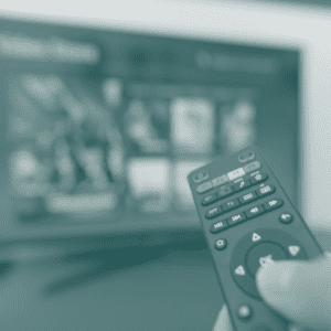 Hand holding TV remote with TV in background