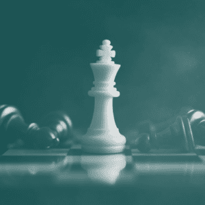 Chessboard with white king standing amongst fallen black pieces
