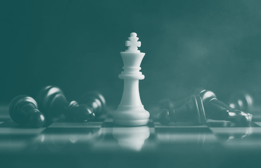Chessboard with white king standing amongst fallen black pieces