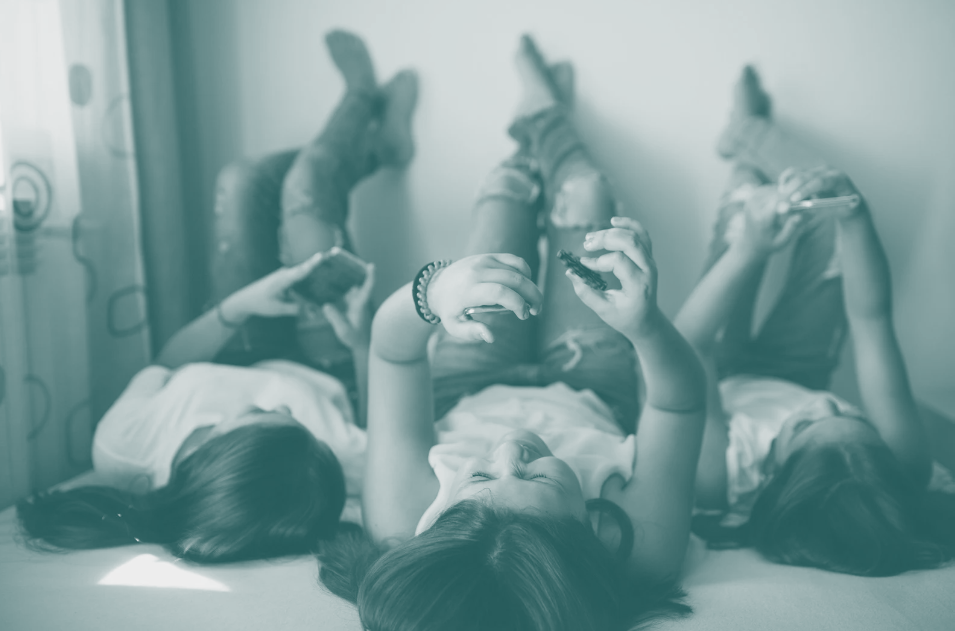 Three teen girls checking their smartphones